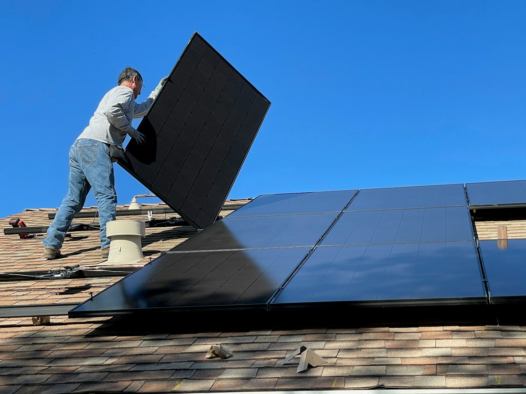 A worker installing solar panels on a residential roof